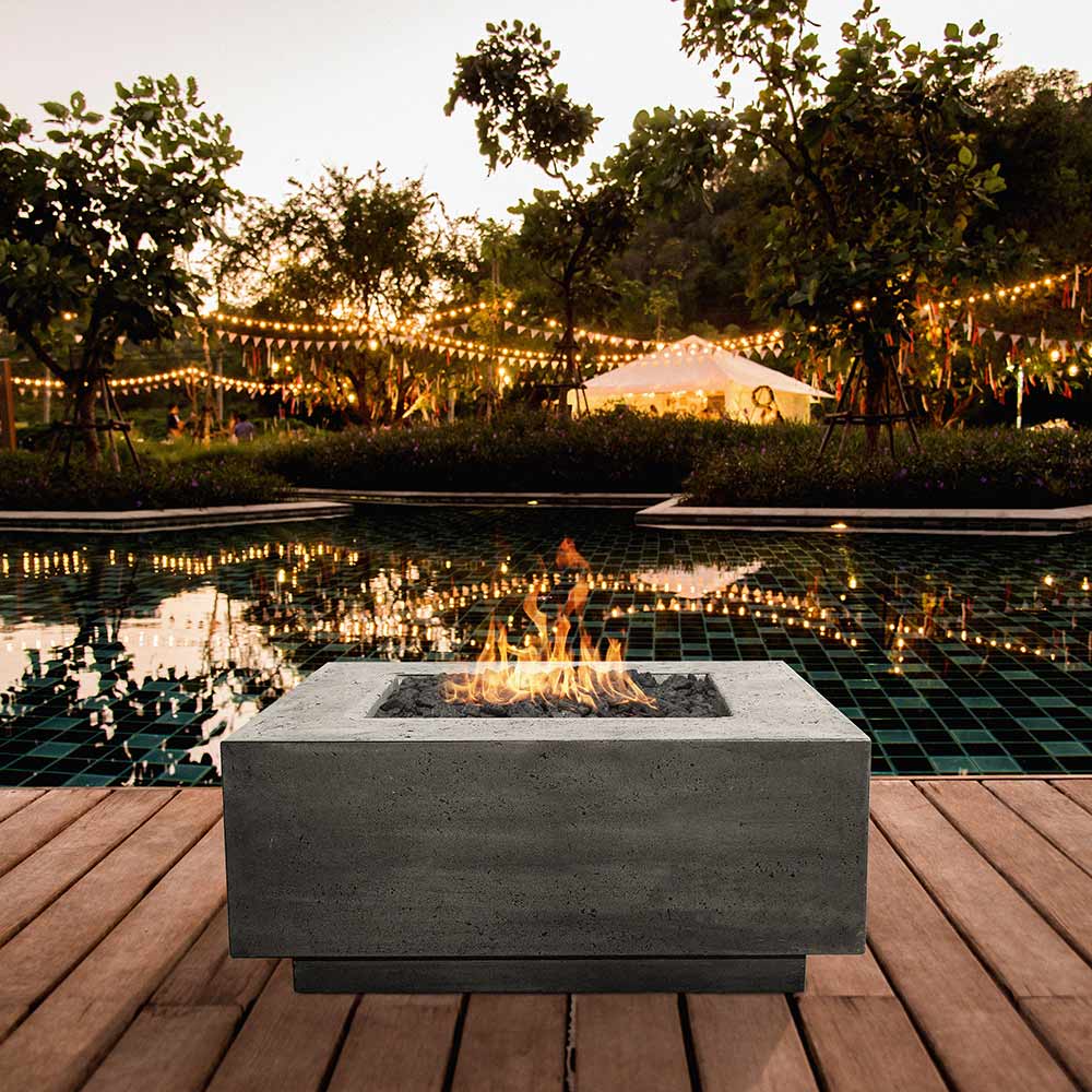 Square concrete gas fire pit with burning gas flame in recessed center
