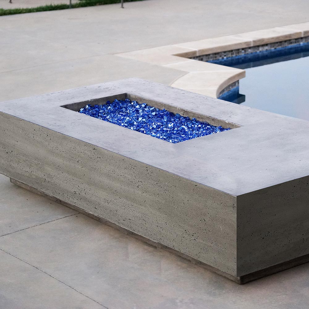 Concrete gas fire pit with rectangular burner opening filled with blue fire media