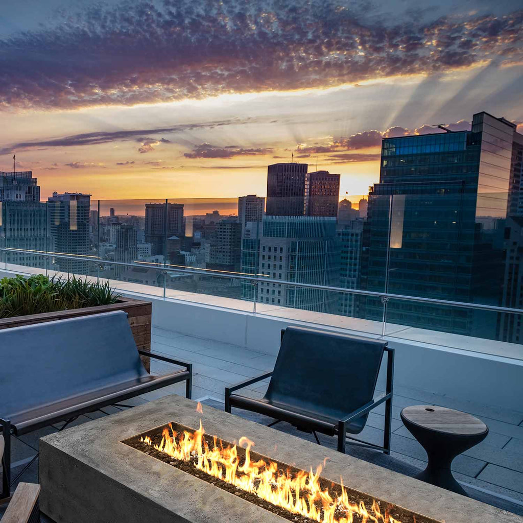 Rectangular concrete gas fire pit with flames over dark lava rocks