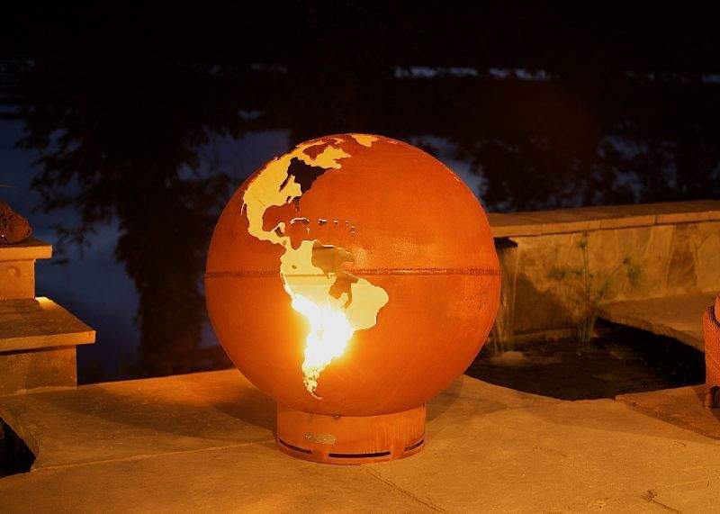 Globe gas fire pit with orange sphere and bright flames showing through continents