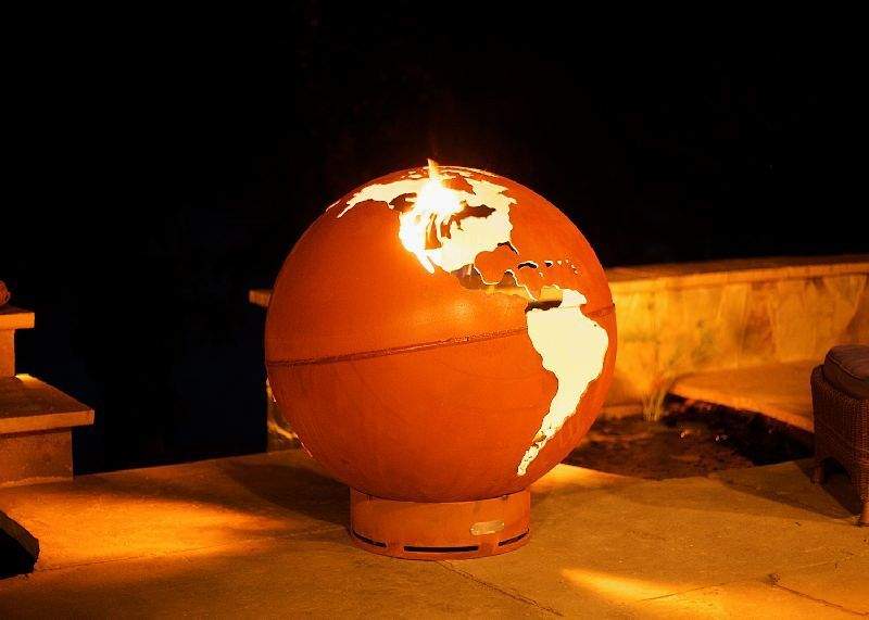 Globe gas fire pit with orange sphere and tall flames burning at center