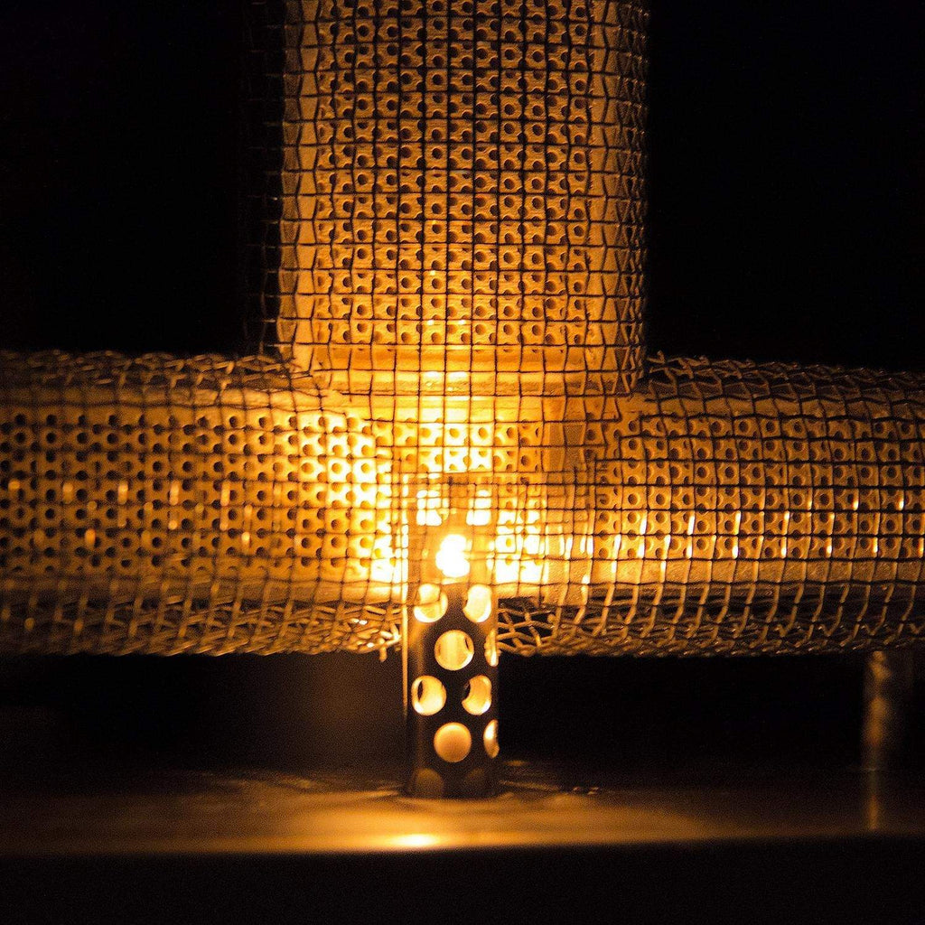 Gas grill burner area with glowing amber flame behind wire grates