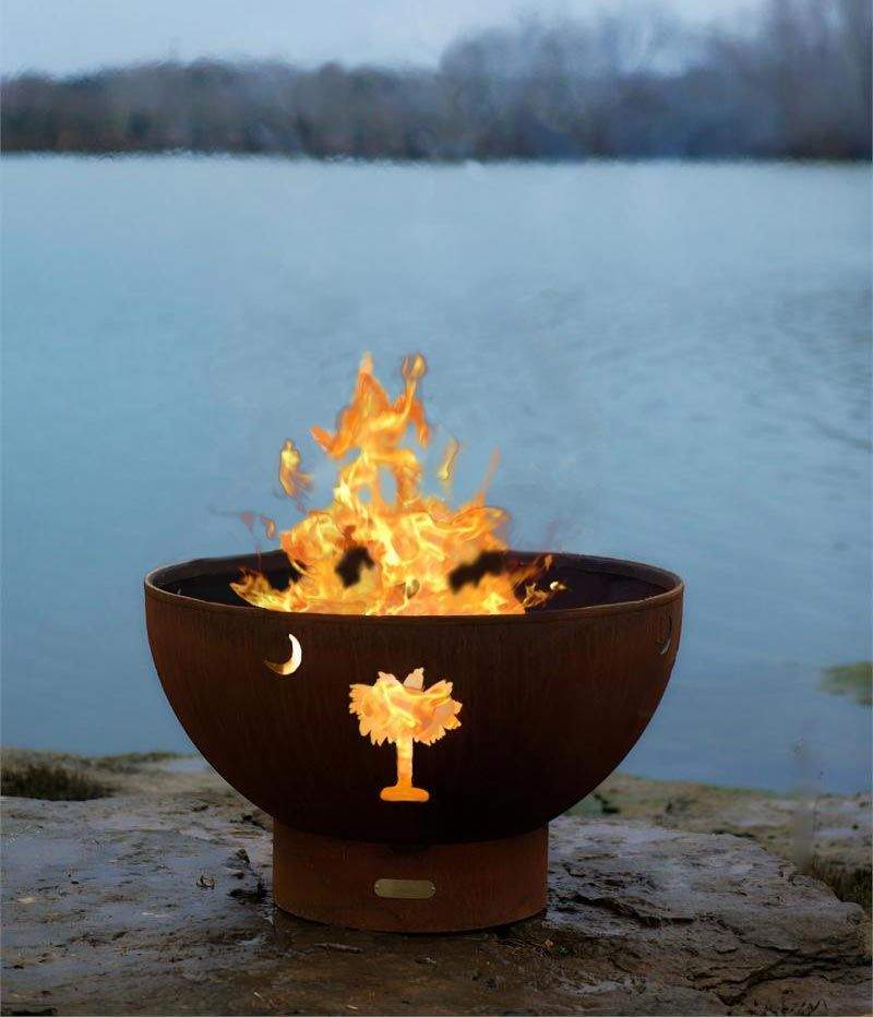Gas fire pit bowl with Tropical Moon artwork and active flames, bronze finish