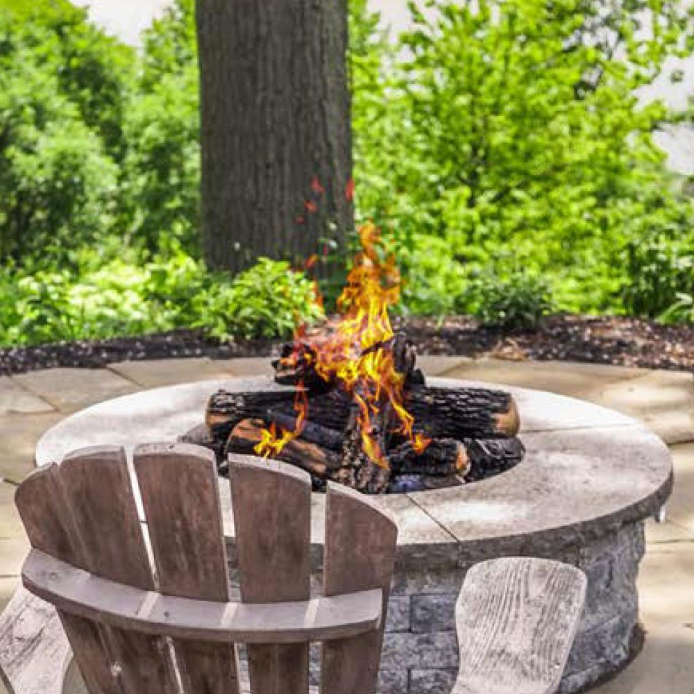 Round fire bowl with burning wood flames in a stone fire pit