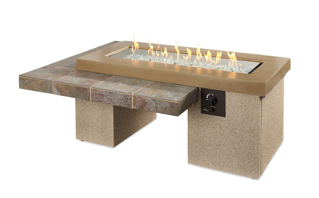 Linear gas fire pit table with tan top, stone-look base, and black ignition/control knob.