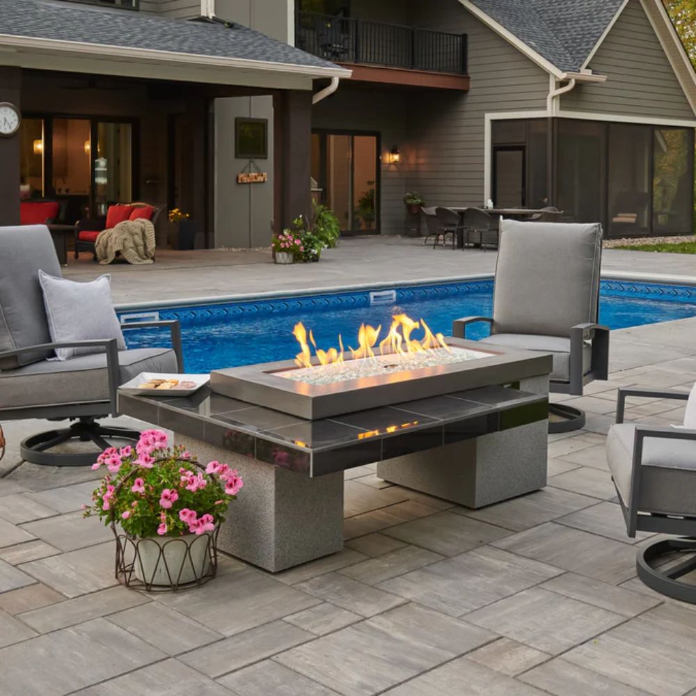 Outdoor linear gas fire pit table with glowing flames and stone-style top
