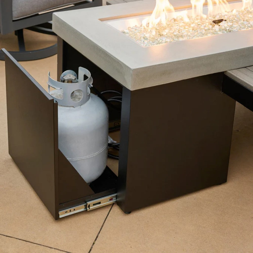 Linear gas fire pit table with open base compartment showing a propane tank