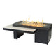 Linear gas fire pit table with black base and light gray top, flames rising from burner