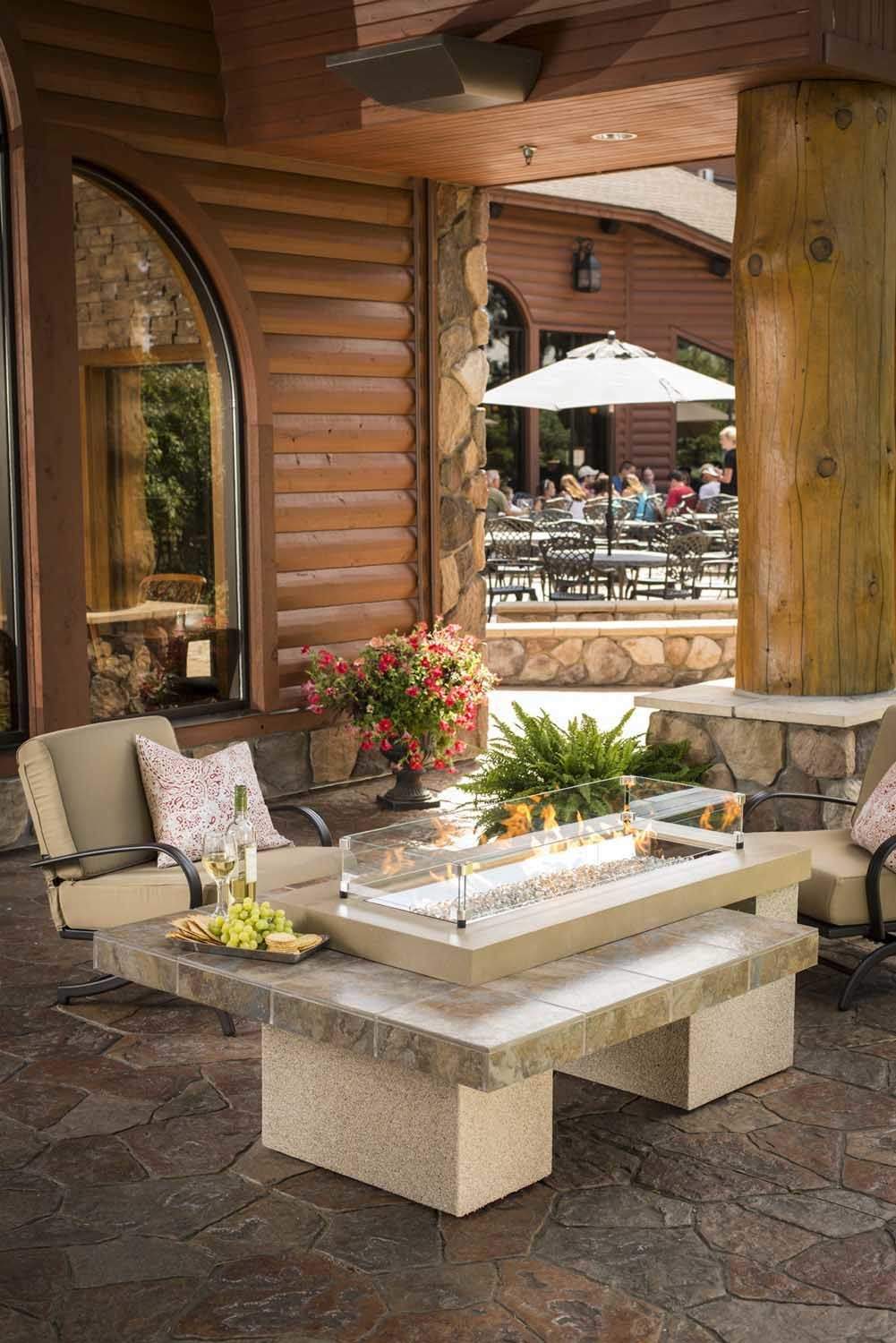 Rectangular glass wind guard on stone outdoor fire table, clear glass with metal frame