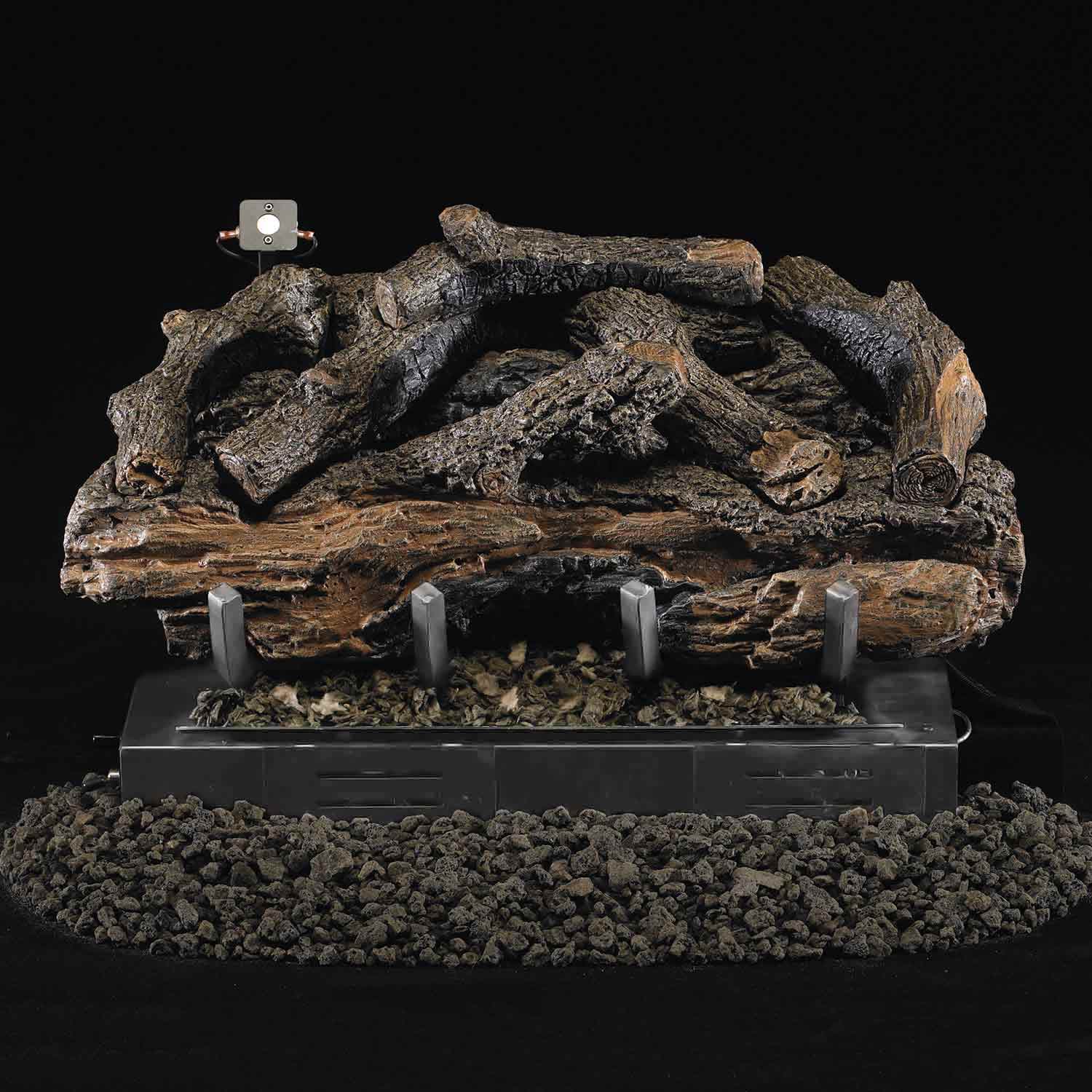 Charred aged gas log set resting on a metal burner base with ember bed and mounting brackets