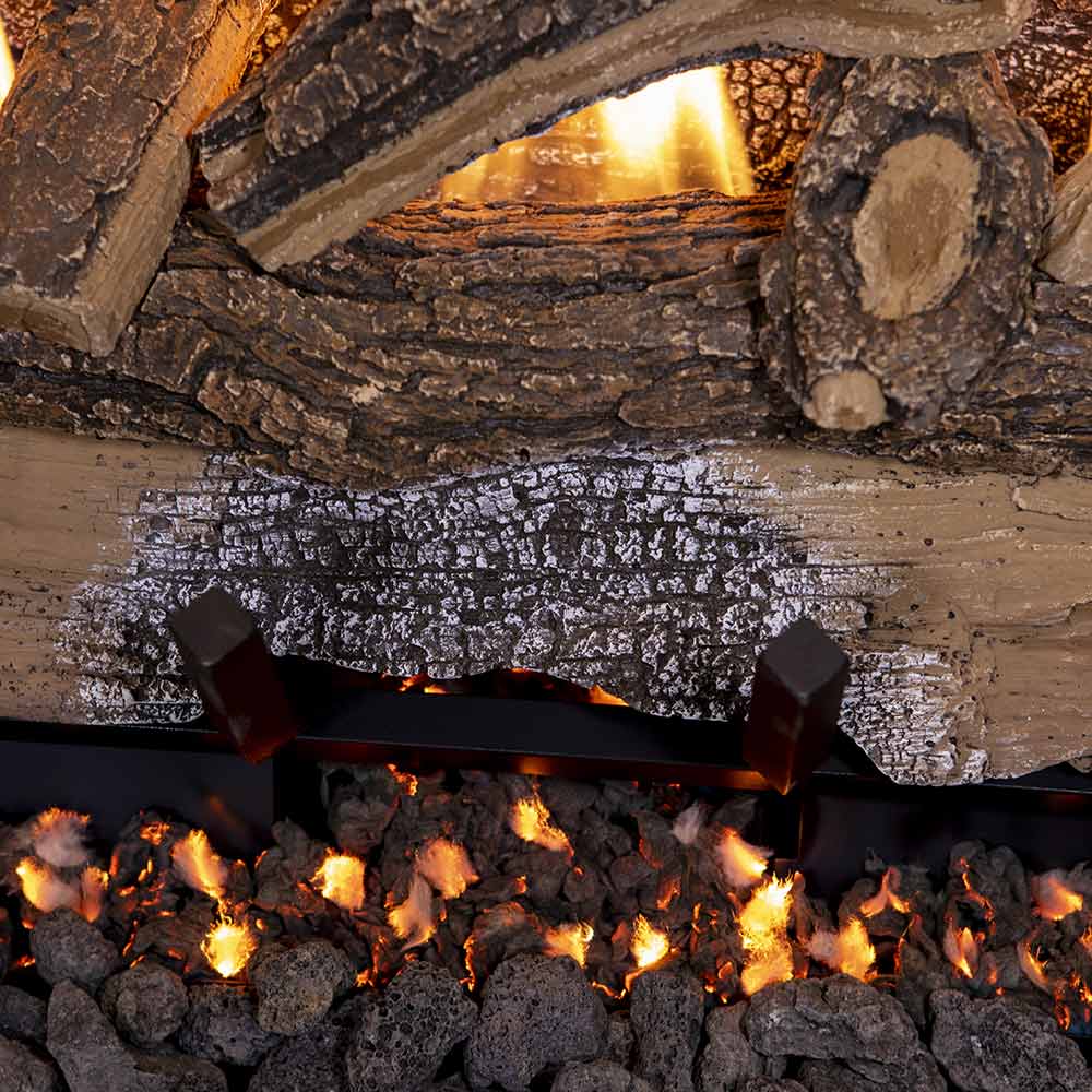Split oak gas logs with burning embers and flame glow behind the log bed