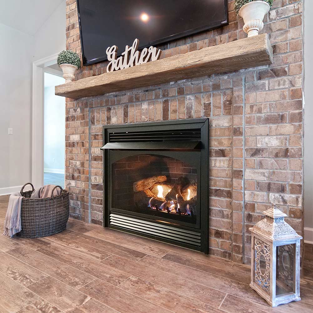Black ventless fireplace insert with glass door and glowing log set flame