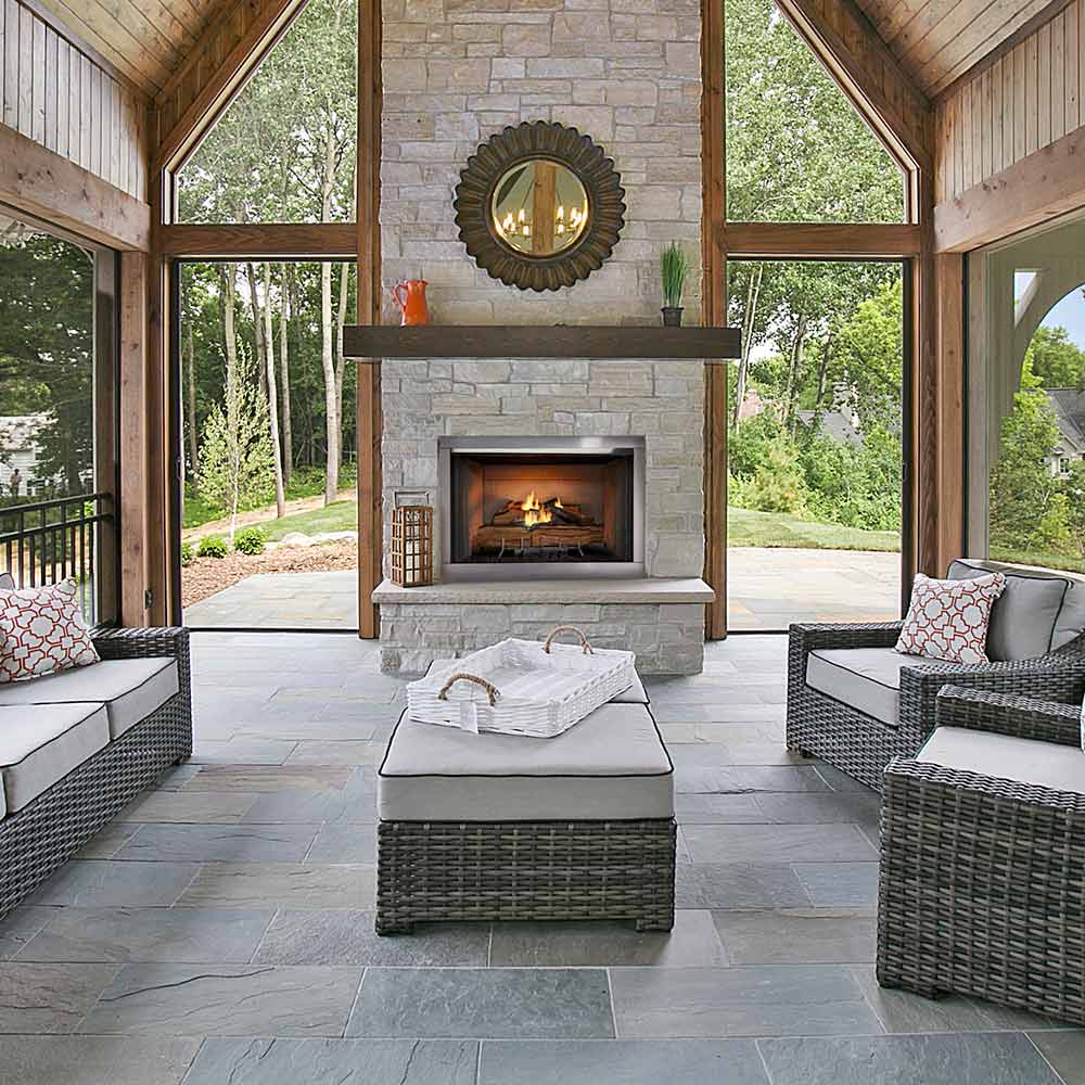 Outdoor gas fireplace in stone outdoor living space, burning logs behind screen