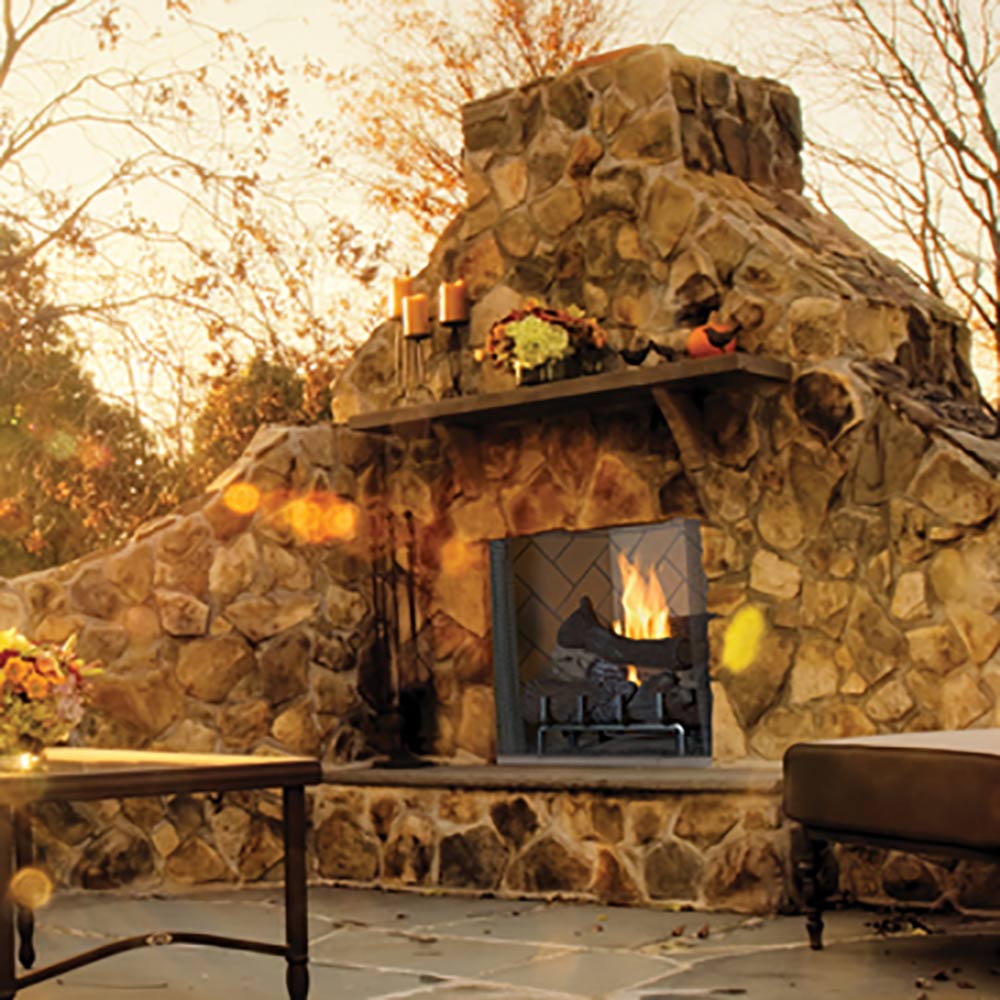 Outdoor gas firebox with stone surround and burning logs, front view