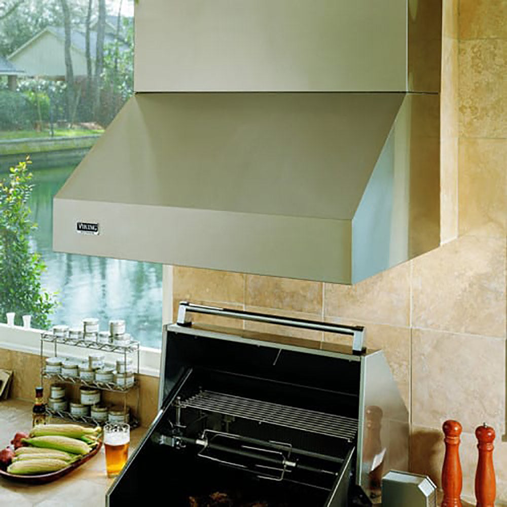 Stainless steel outdoor ventilation hood above grill, interior fan and duct opening visible
