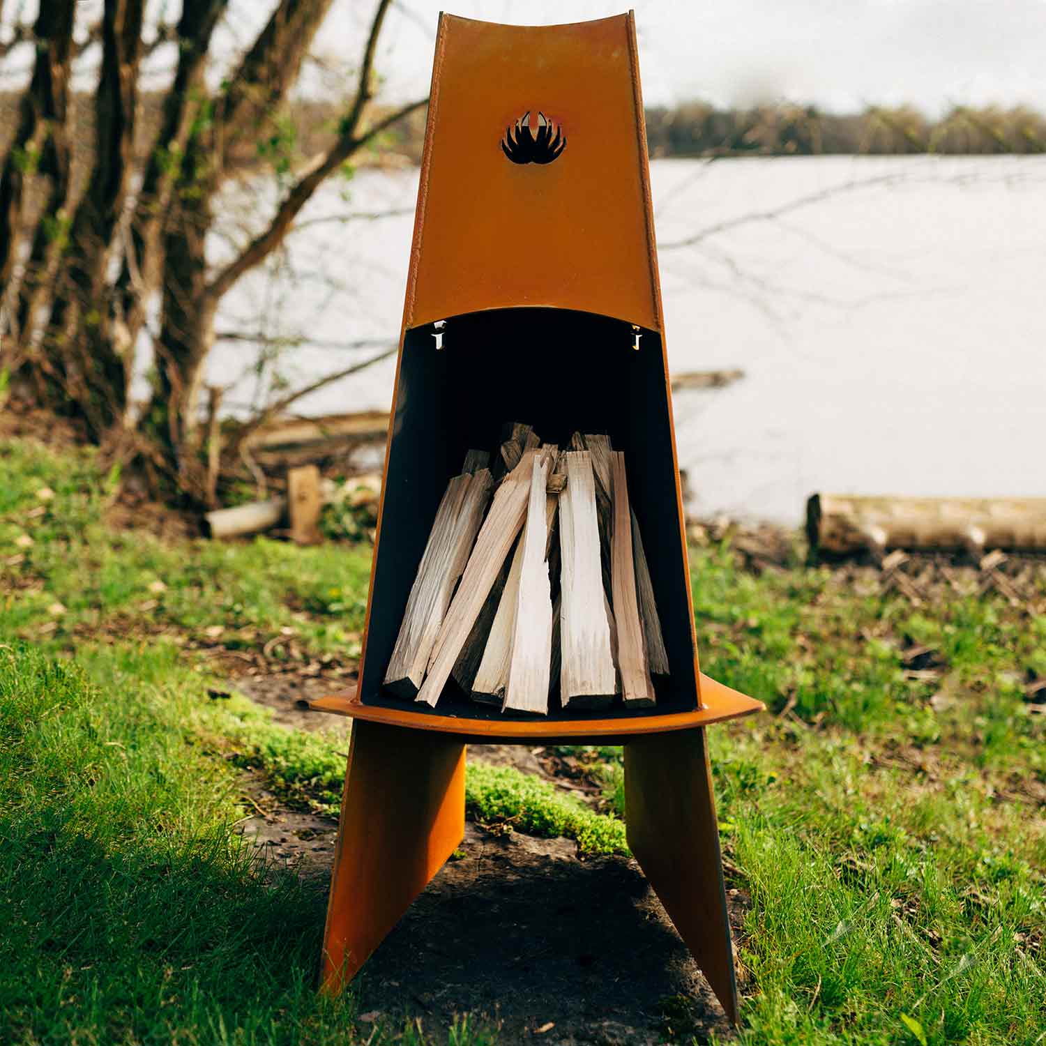 Wood fire pit with stacked split logs inside, triangular orange bowl and black base