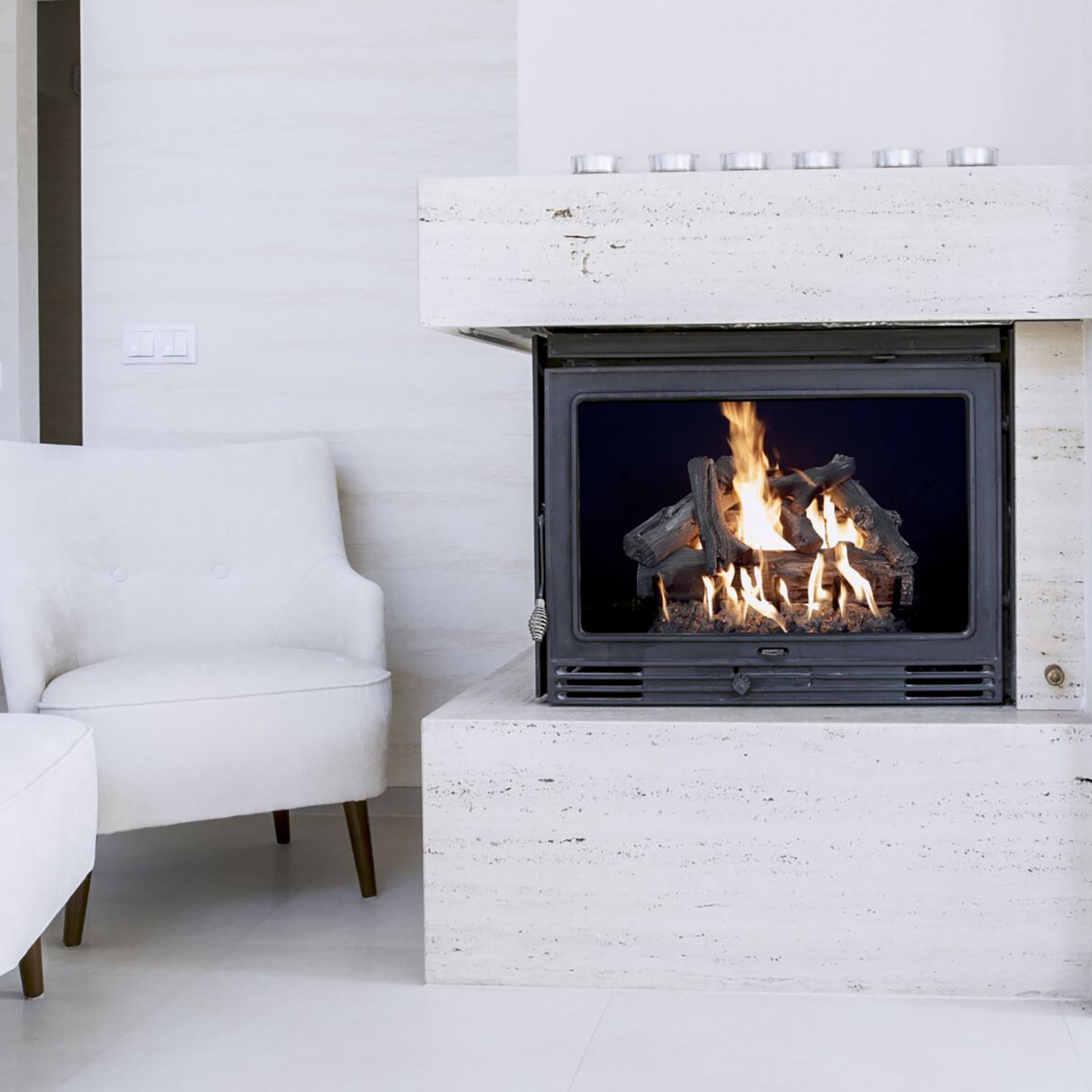 Vented gas log burner inside a black firebox opening with driftwood-style logs and flames