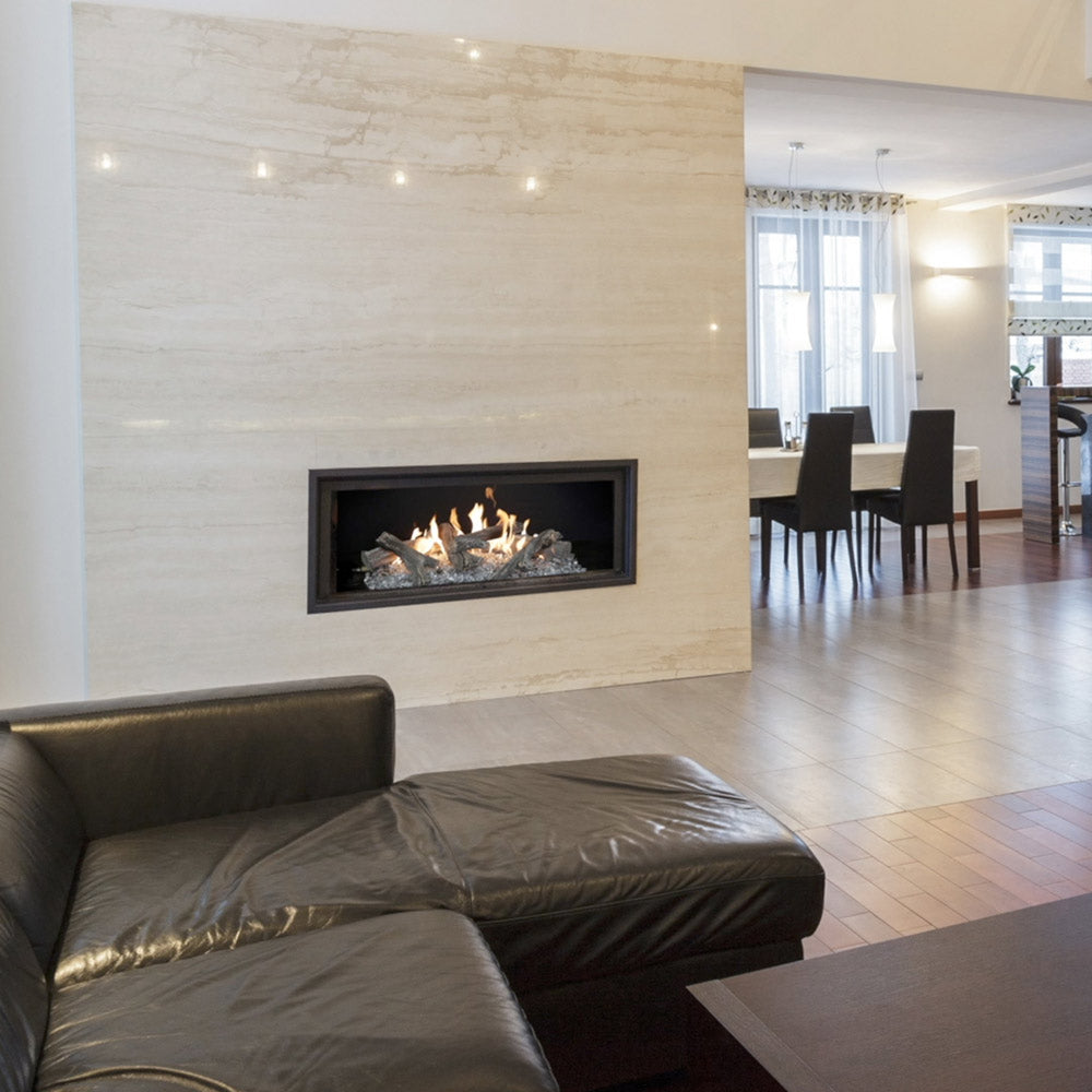 Indoor linear gas log fireplace with burning dark logs inside a black trim frame