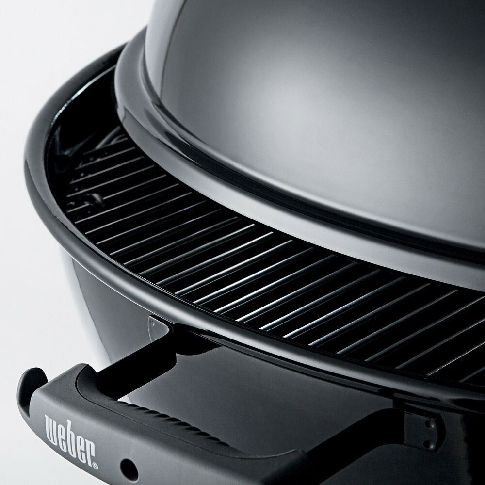 Charcoal grill lid interior with metal vent and black cooking grate close-up