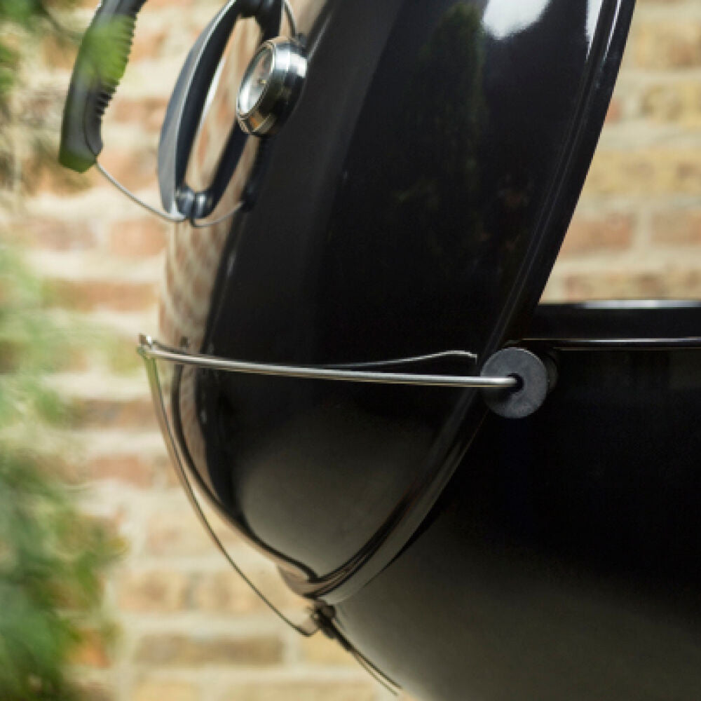 Charcoal grill lid latch and side handle on black grill body