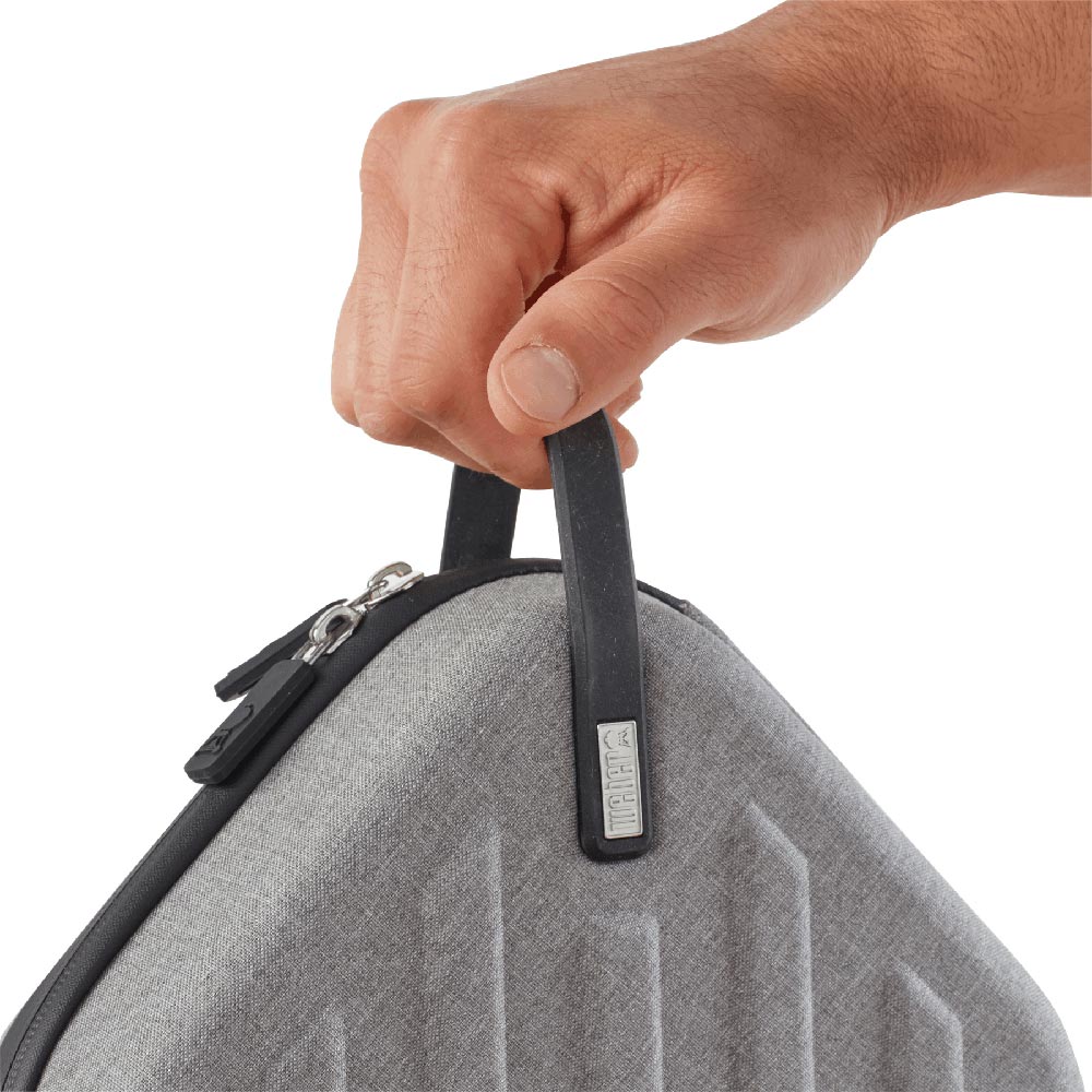 Hand holding gray travel case by black handle and zipper pull