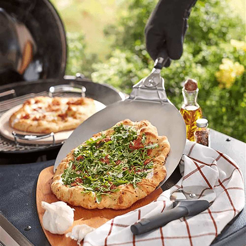 Pizza paddle lifting a topped slice; stainless blade with black handle