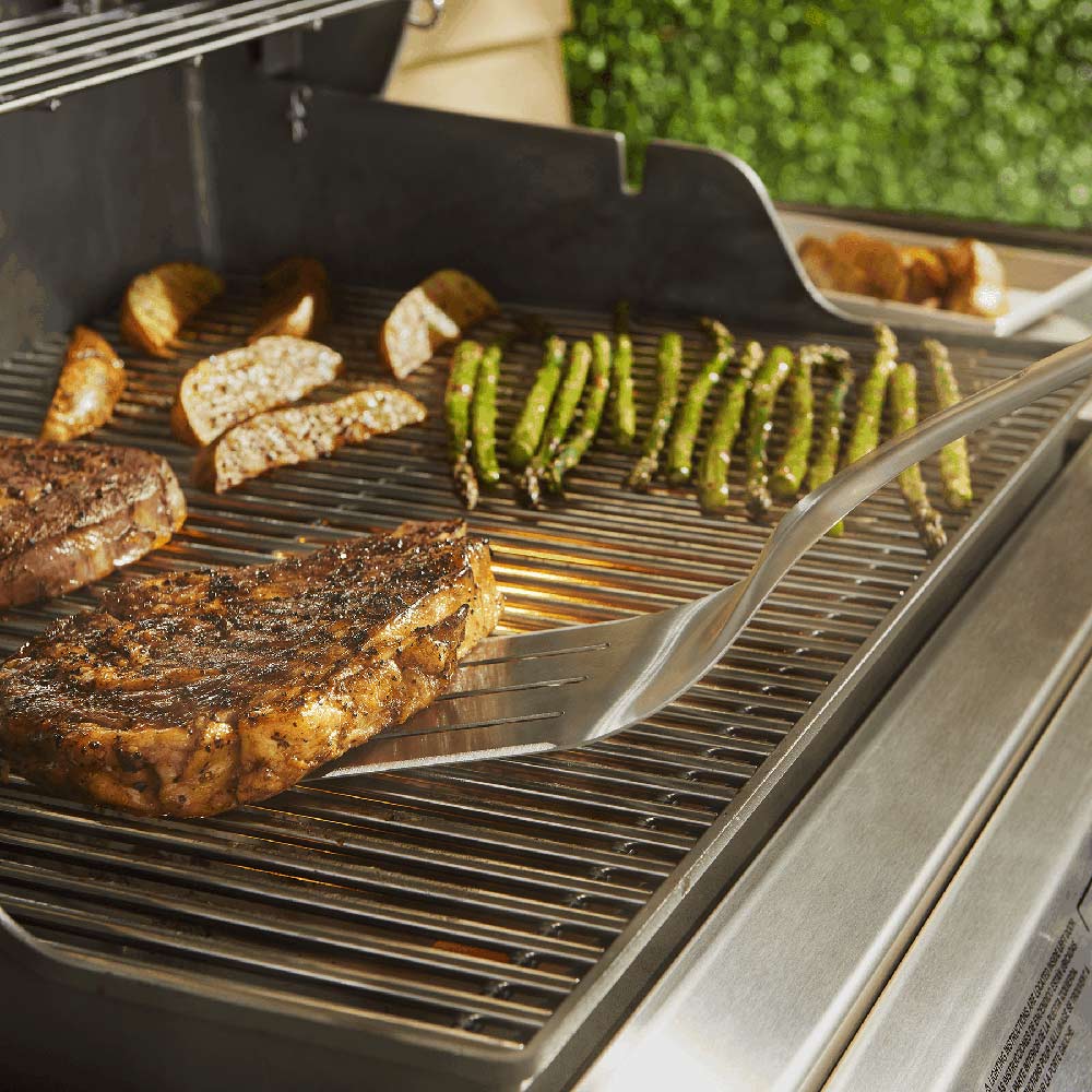 Stainless steel grill spatula on barbecue grates, lifting grilled food
