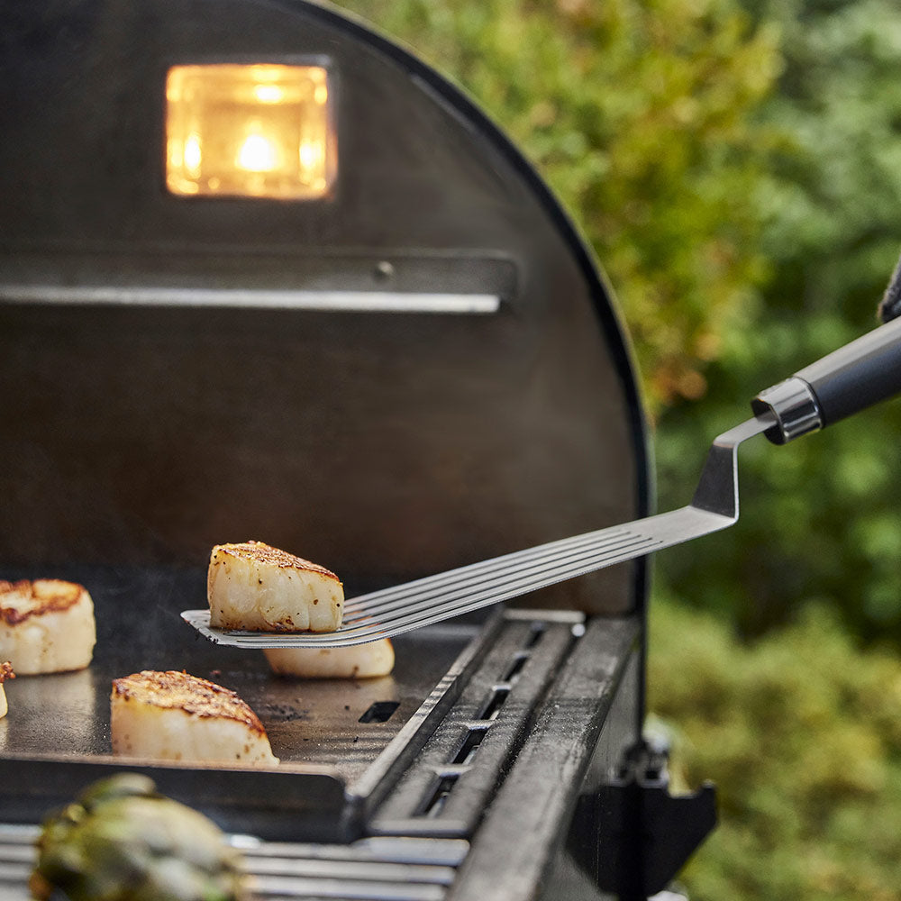Weber flexible griddle spatula lifting food on a grill griddle