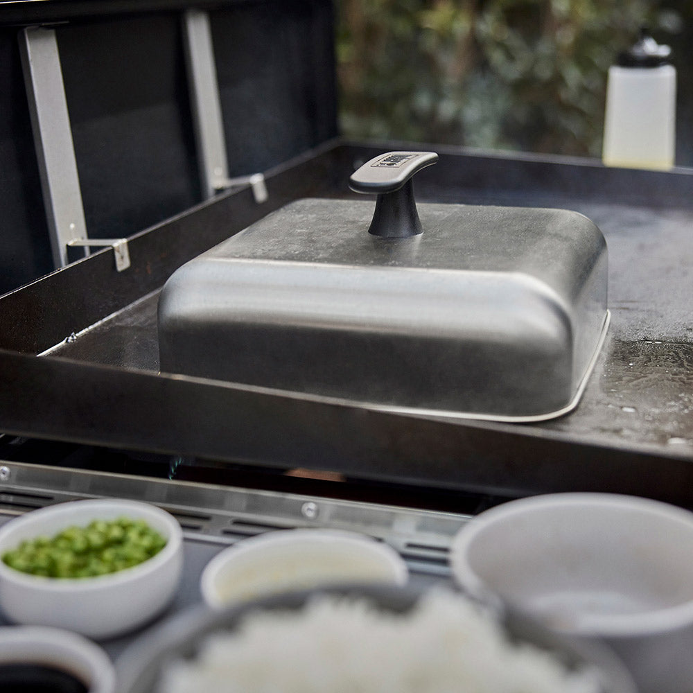 Weber griddle basting dome on countertop grill grate with cooktop trays below