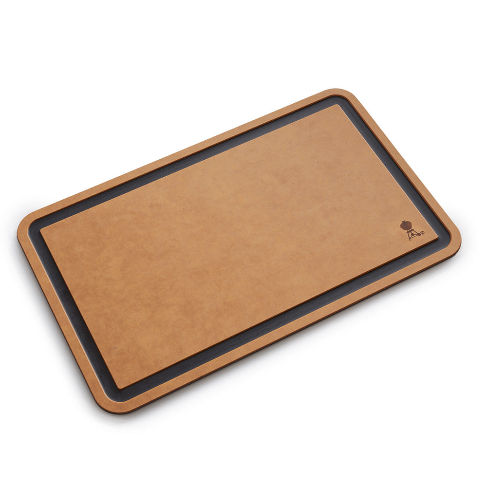 Cutting board with tan surface and dark border, angled view showing rounded frame edge.