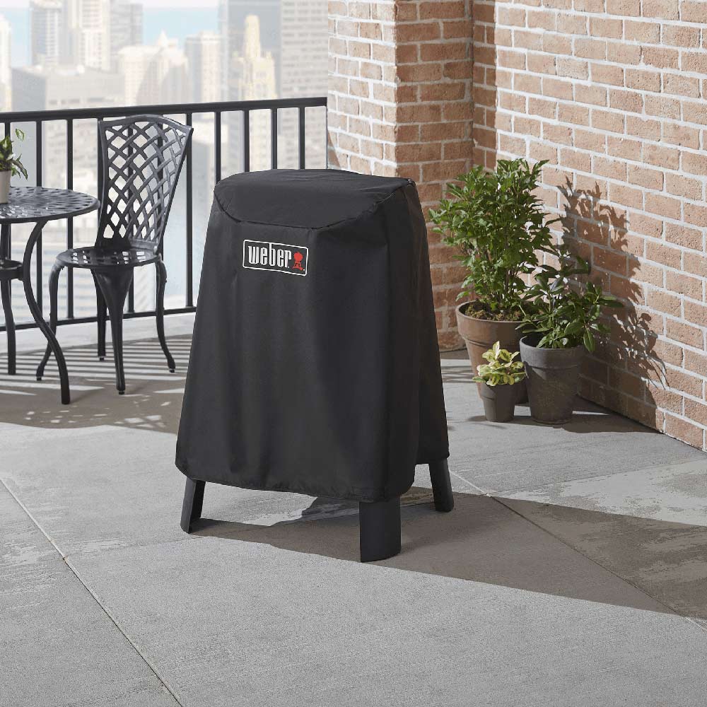 Black Weber grill cover over grill on stand, secure domed top and bottom hem