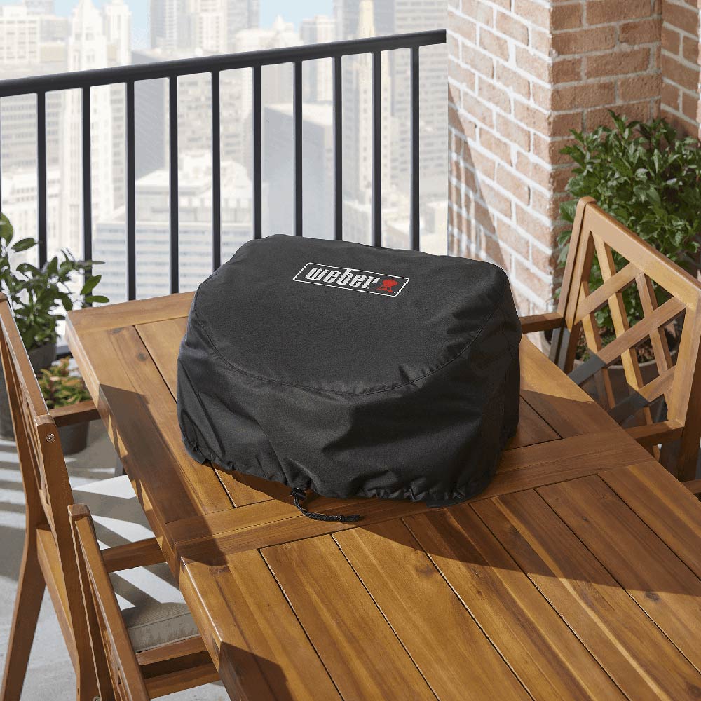 Weber premium grill cover on outdoor grill, black with Weber logo