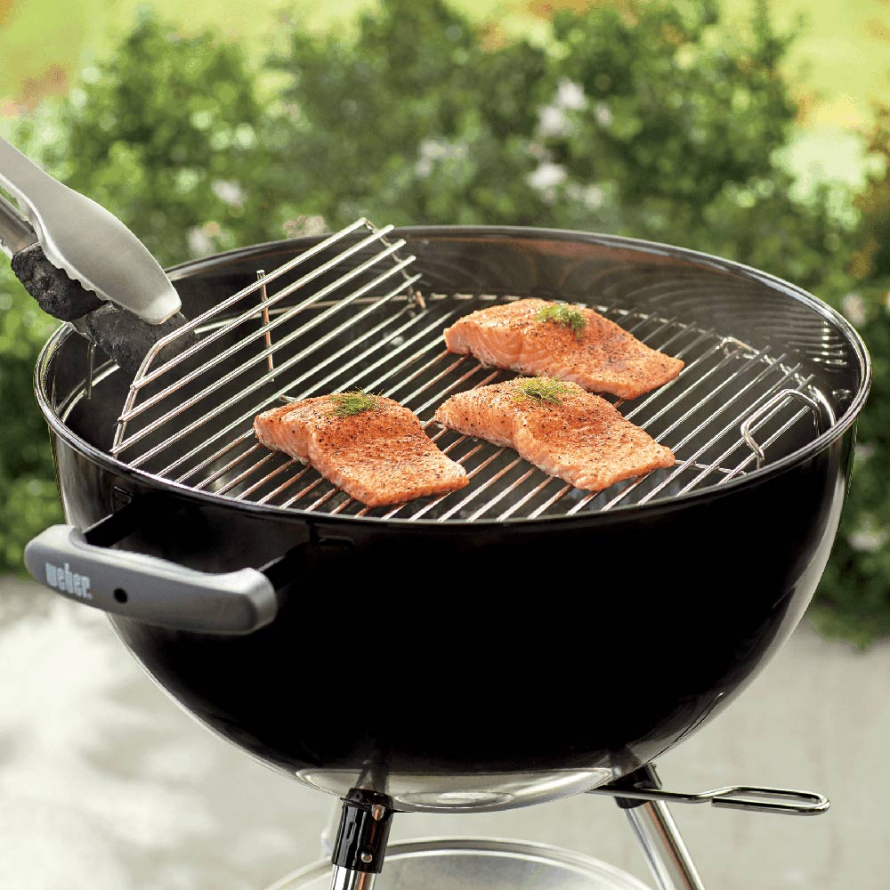 Charcoal grill hinged cooking grate with wire bars, holding several cutlets