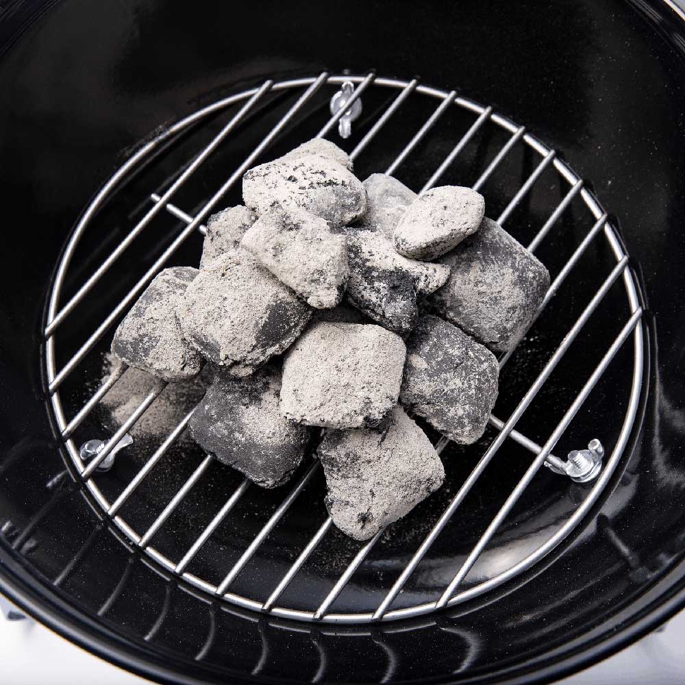 Charcoal grate with wire rails and charcoal briquettes inside grill