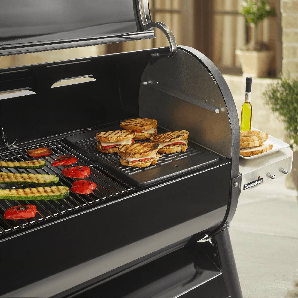 Outdoor grill with griddle plate and cooktop, showing vegetables and meat on grates