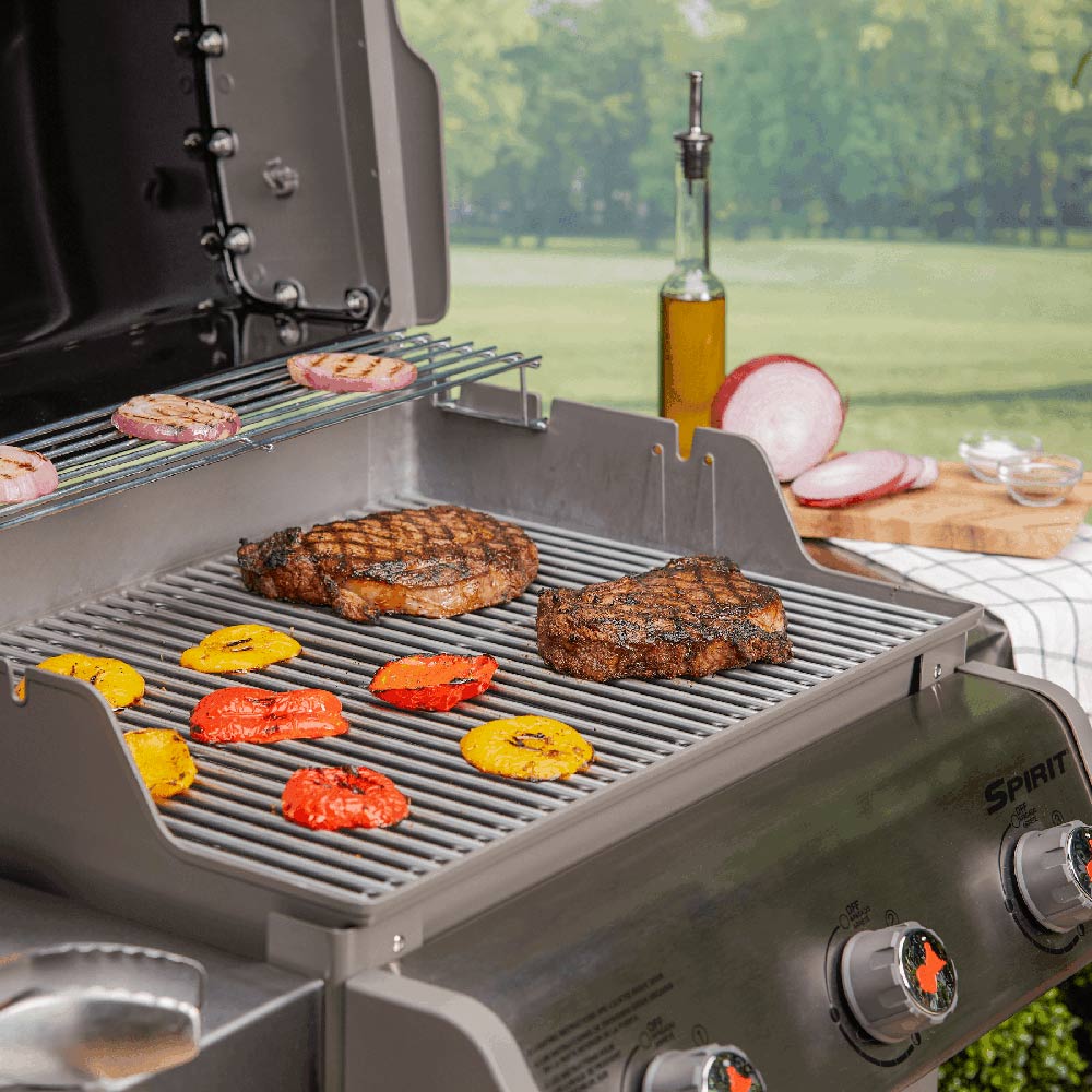 Stainless steel grill cooking grates on a gas grill with food cooking on top