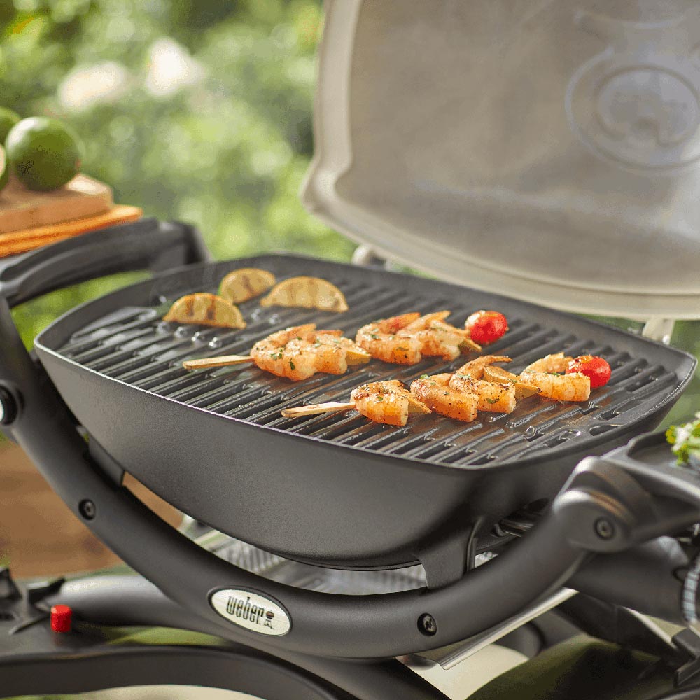 Weber grill grates installed on a gas grill with skewers of food on top
