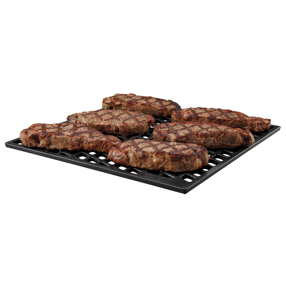 Dual-sided sear grate with browned steaks on a black metal grid