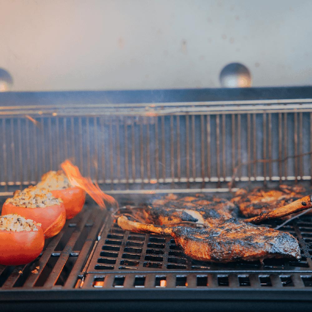 Sear grate on grill with browned meat and orange vegetables cooking