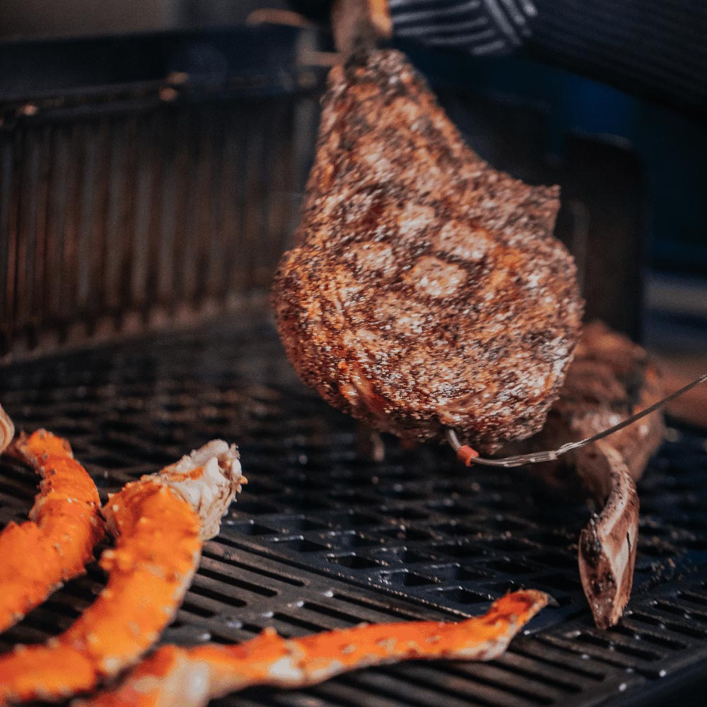 Sear grate with a browned steak and orange vegetables on the grid