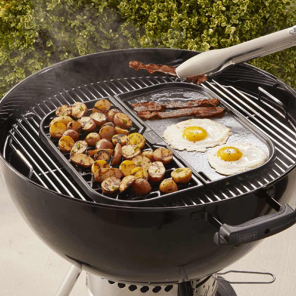 Round grill with griddle insert cooking two sunny-side eggs and roasted potato bites
