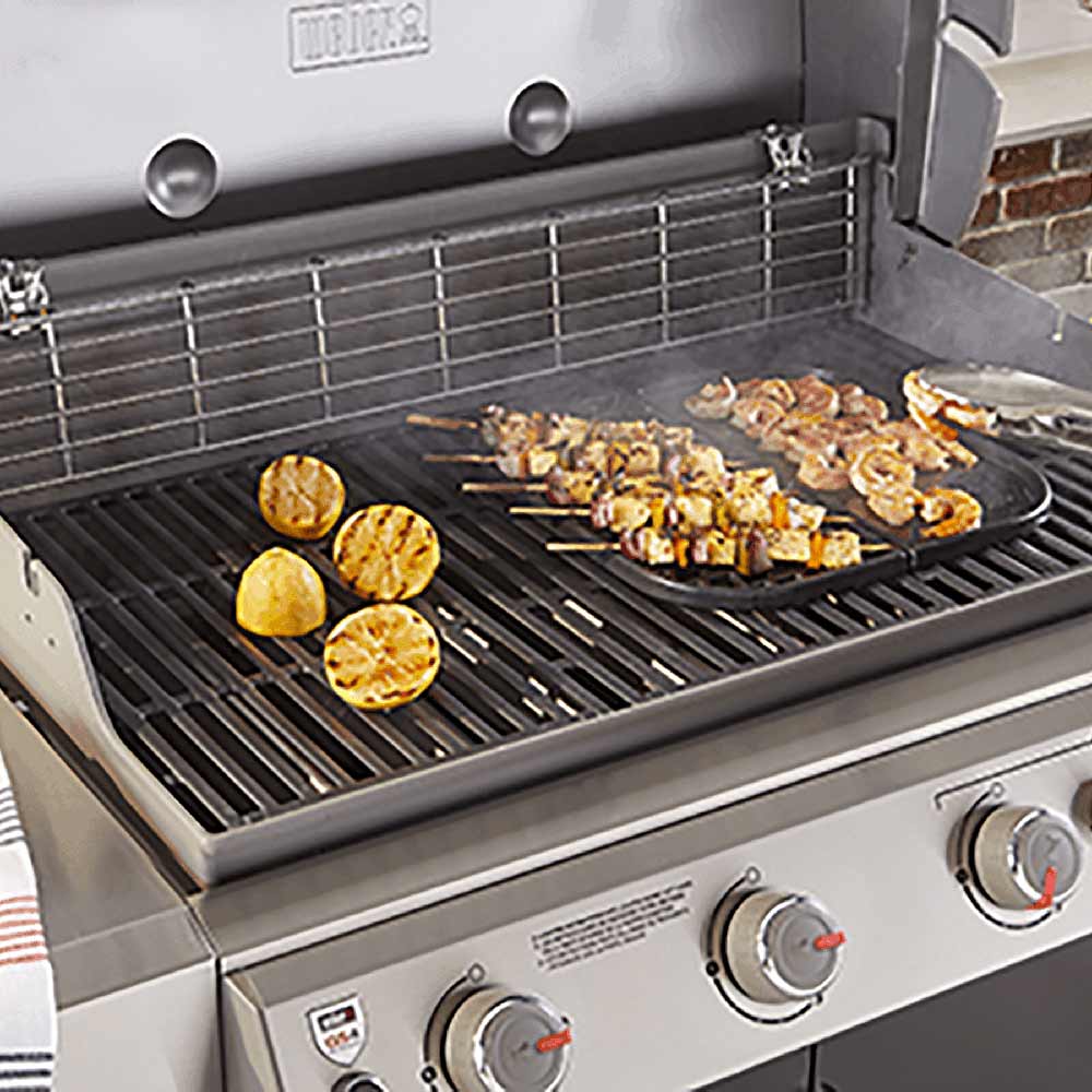 Griddle insert on grill with sliced potatoes and chopped food cooking over grates