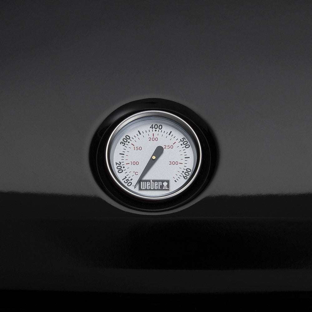 Temperature gauge dial with numbered scale and Weber logo on black grill