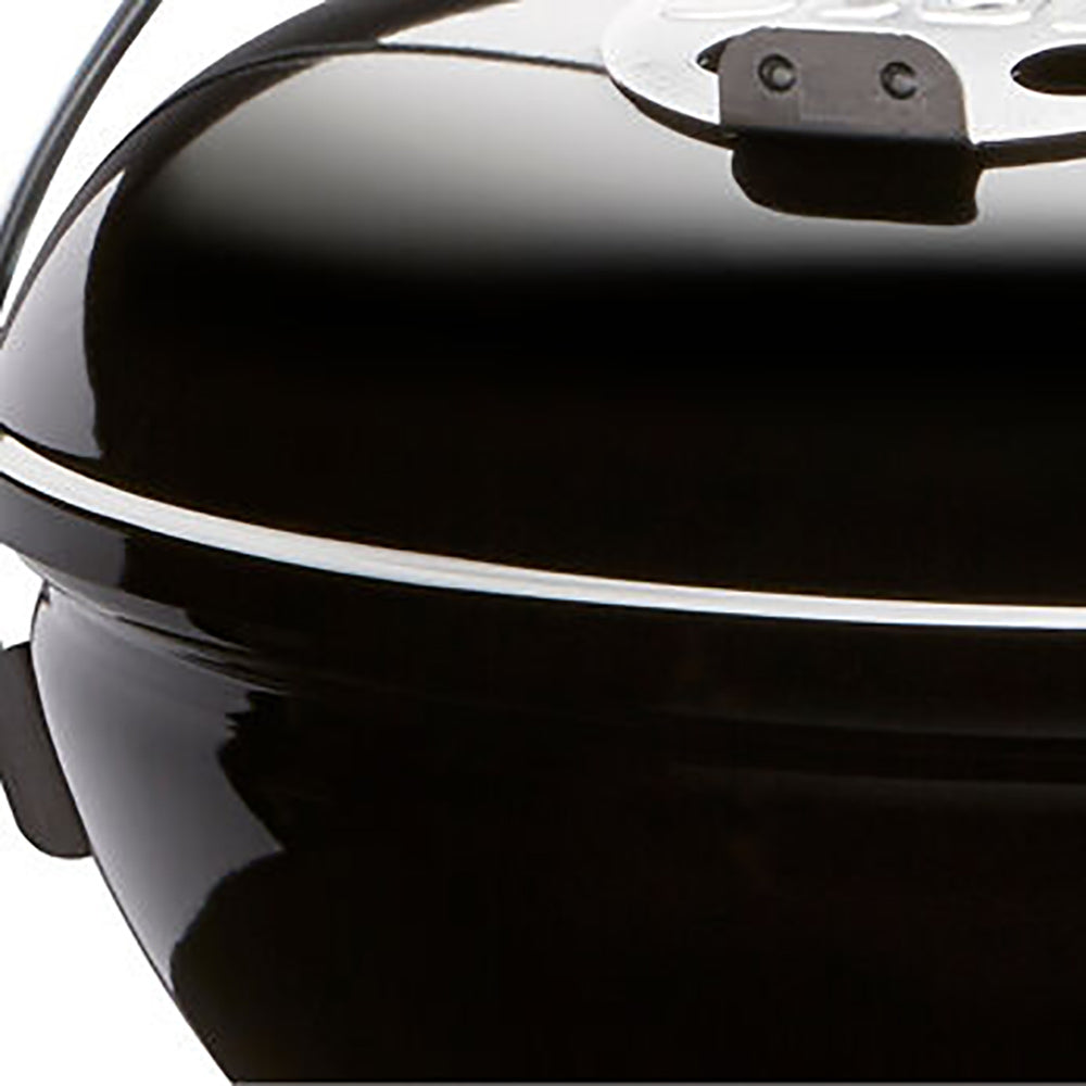 Close-up of dome lid and handle latch on a black portable charcoal grill.