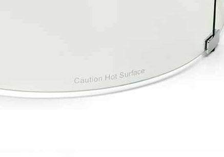 Clear glass wind guard with curved base edge labeled "Caution: Hot Surface"