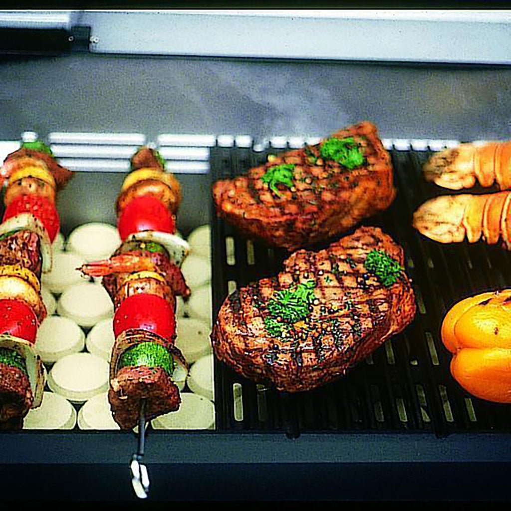 Cooked food on grill grates with skewers and steak pieces under an open lid