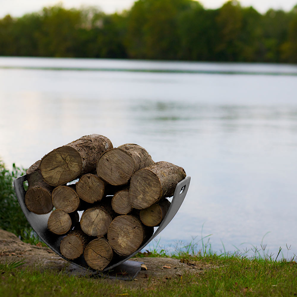 Stainless steel log rack with curved wings holding stacked firewood
