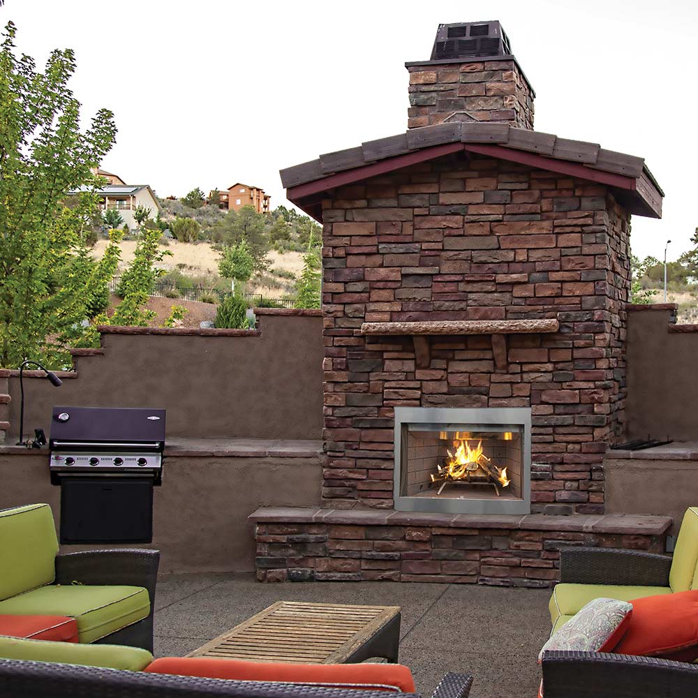 Outdoor wood burning fireplace with stone veneer chimney and open firebox flames