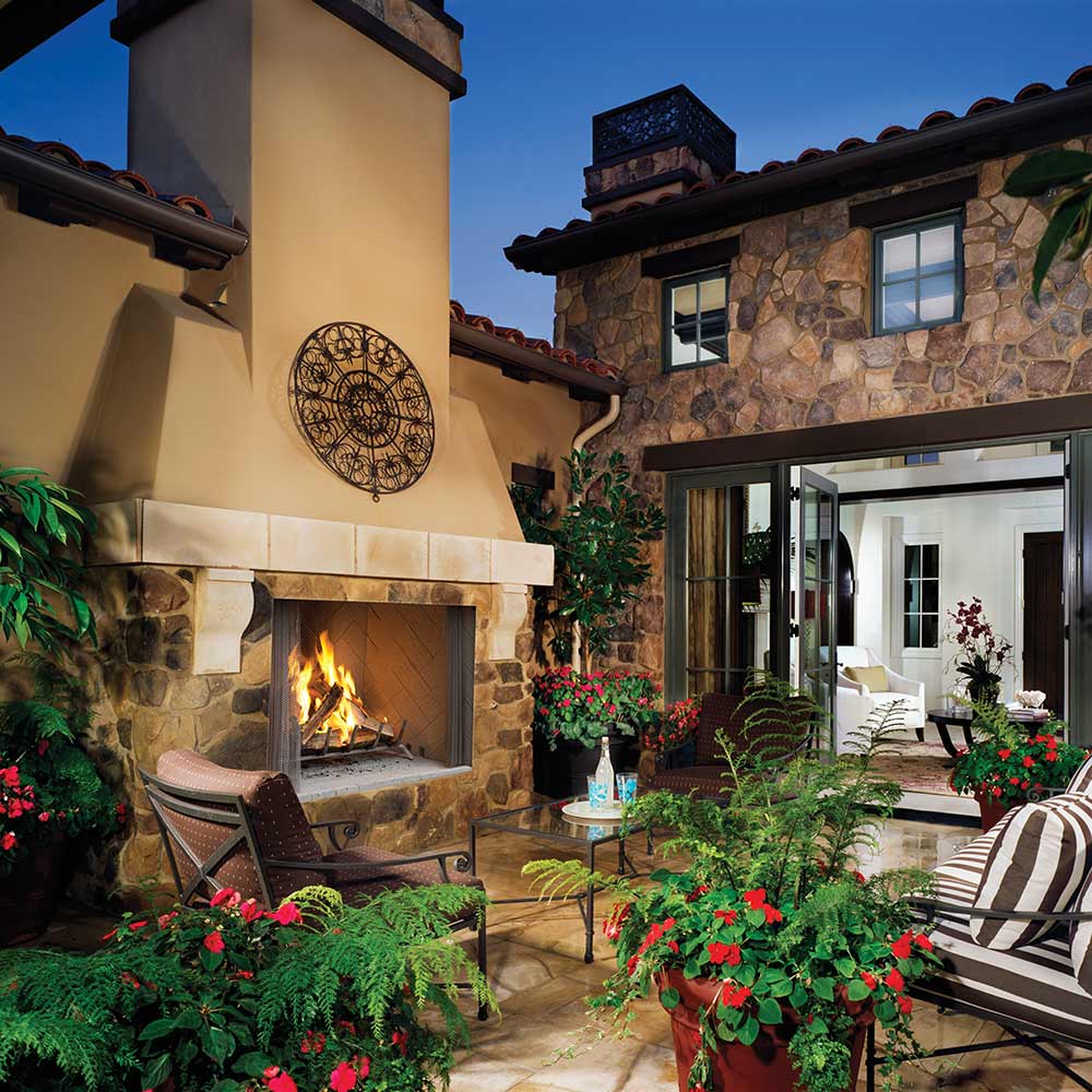 Outdoor wood-burning fireplace in stone surround with burning fire and open hearth