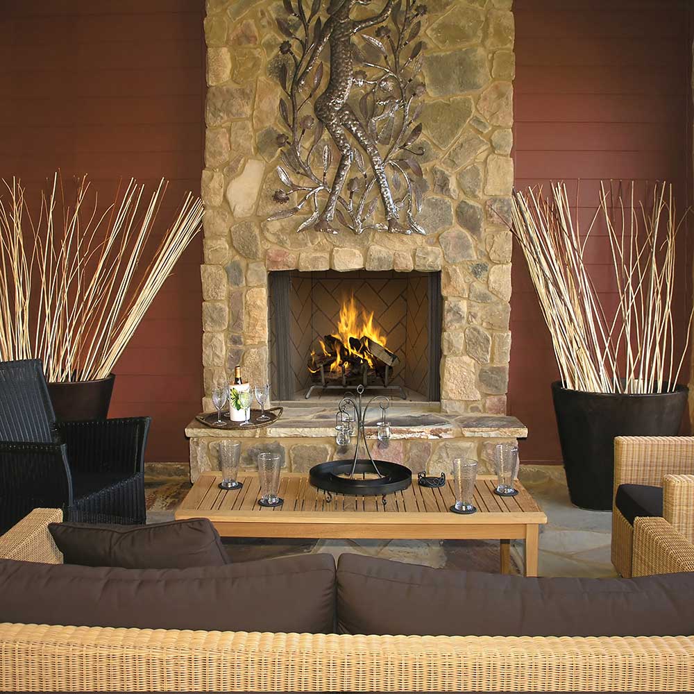 Outdoor wood-burning fireplace with stone surround, burning logs, and tiled firebox
